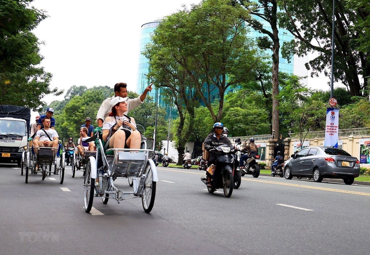 Du khách quốc tế tham quan trung tâm Thành phố Hồ Chí Minh bằng xích lô. (Ảnh: Hồng Đạt/TTXVN)