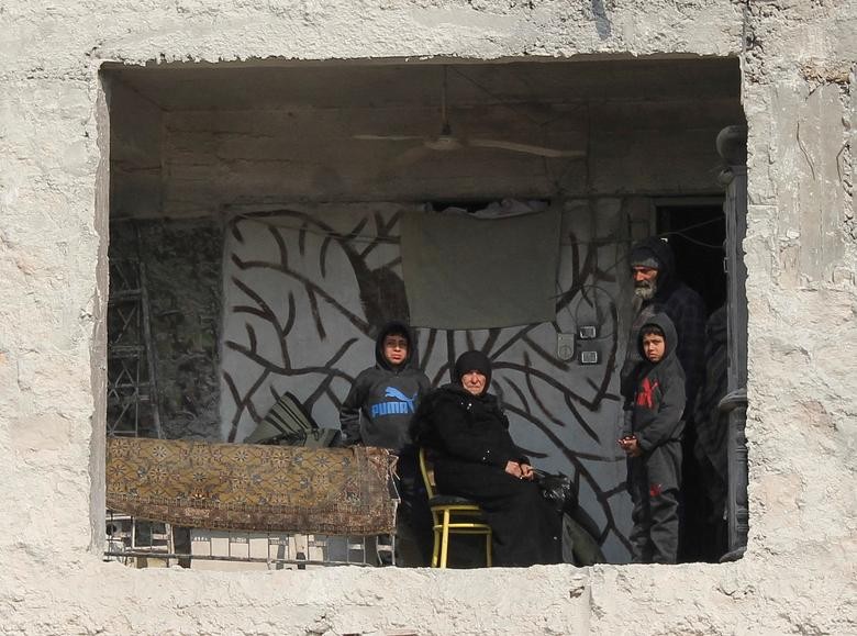 Người phụ nữ Syria Amina Raslan ngồi cùng con trai và các cháu tại ngôi nhà bị hư hại một phần sau trận động đất kinh hoàng ở Aleppo, Syria, ngày 13/2. (Nguồn: Reuters)