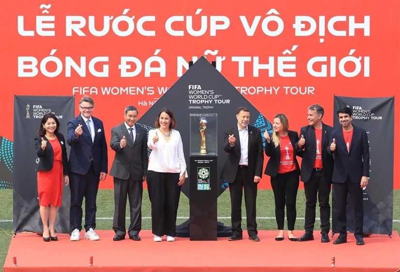 Head coach of the women's national football team Mai Duc Chung (third from left), head coach of the men's national football team Philippe Troussier (second from left) and FIFA representatives pose for a photo besides the FIFA Women's World Cup trophy on March 4. (Photo: VNA)