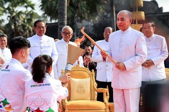 Cambodia's King Norodom Sihamoni (2nd right) lights the torch with a candle lit from the sun's rays as Prime Minister Hun Sen (right) looks on during a ceremony prior to the 32nd SEA Games at Angkor Wat temple in Siem Reap on March 21. AFP/VNA Photo
