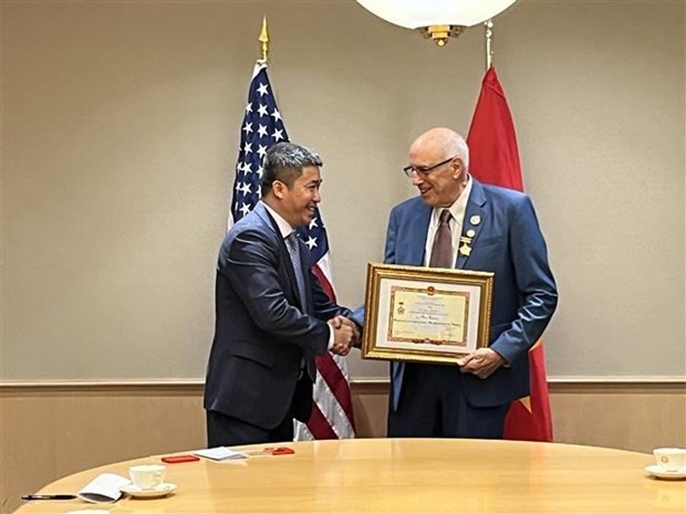 VUFO Vice President and General Secretary Phan Anh Son (L) presents the insignia to Ron Carver, a social activist for peace and a scholar who participated in demonstrations demanding an end to the American war in Vietnam. (Photo: VNA)