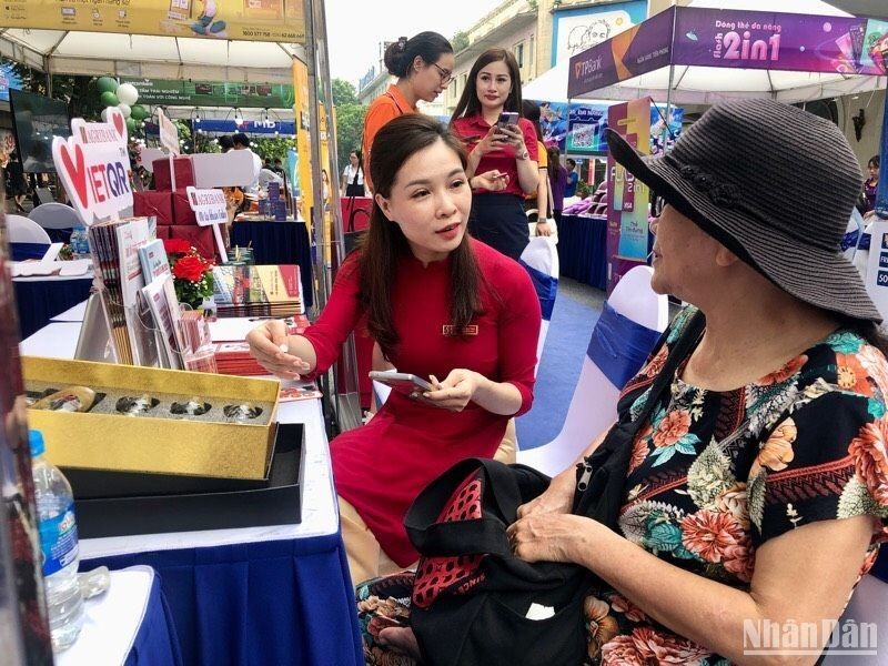 A bank employee guides a woman on how to make non-cash payments. (Photo: NDO)