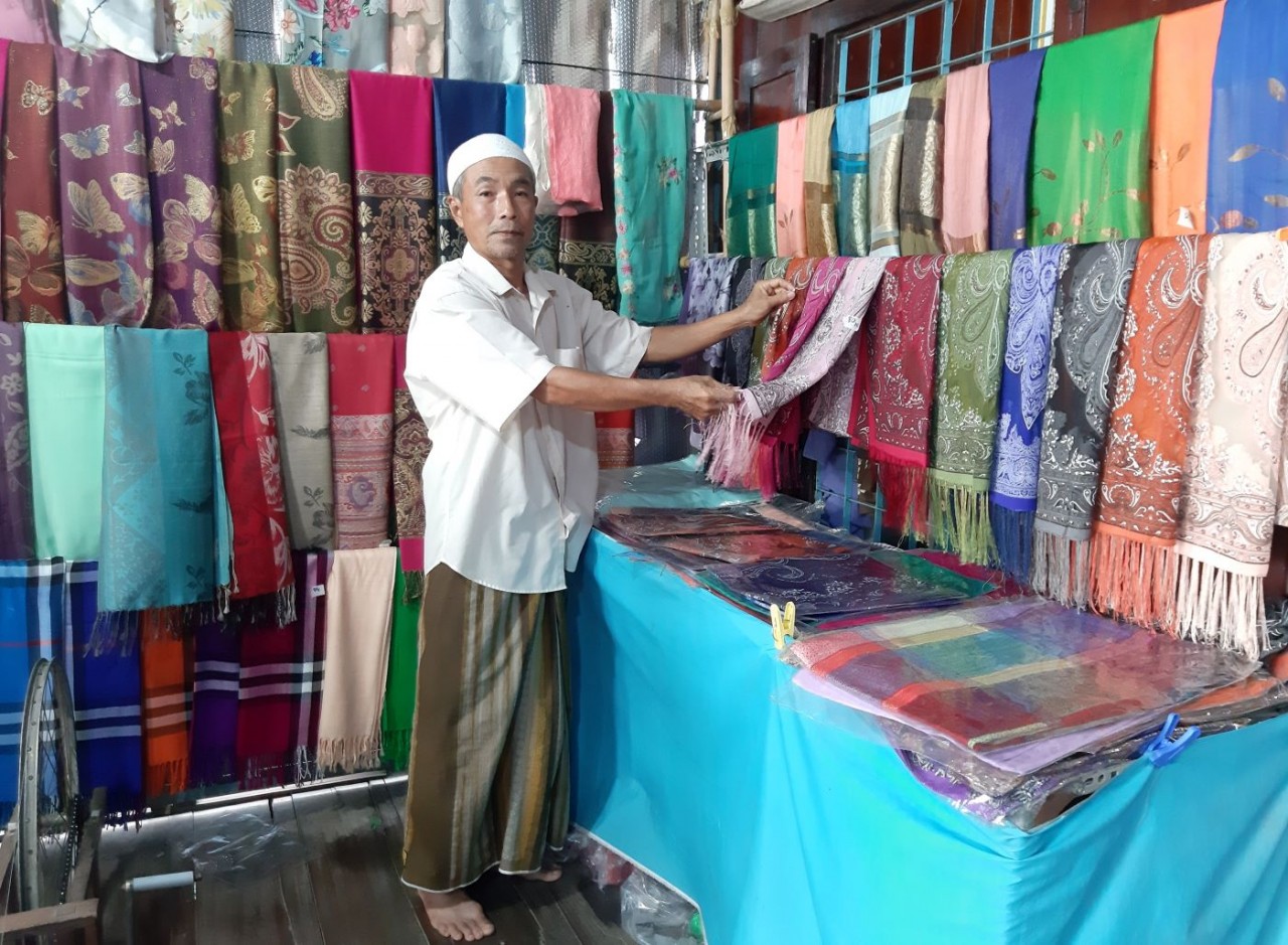 Ông Mohamad ở ấp Phũm Soài (xã Châu Phong) giới thiệu sản phẩm dệt thổ cẩm Châu Giang với du khách. (Ảnh: Phương Nghi)