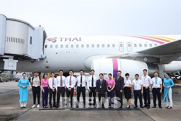 Staff members of Thai Airways pose for a photo in front of the carrier's plane landing at Noi Bai International Airport on October 29. (Photo courtesy of Thai Airways)