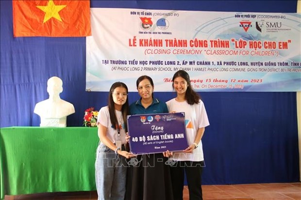 The YMCA Vietnam and Singaporean students present the school 40 sets of English books and various learning tools at the ceremony. (Photo: VNA)