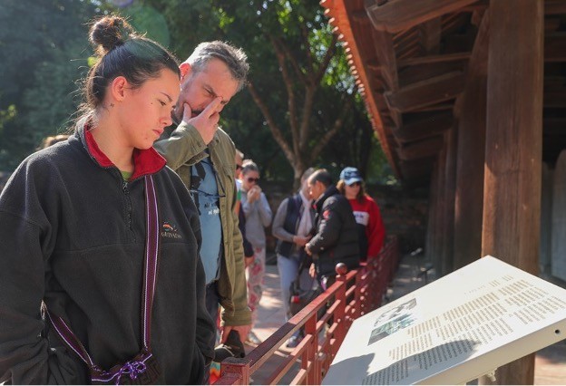 Tourists read information about the doctoral stele at the Temple of Literature. (Photo: VNA)