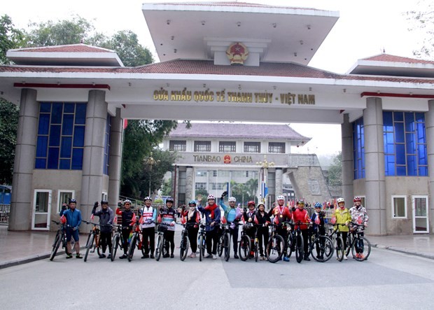Participants in the bicycle tour pose for a photo at the Thanh Thuy International Border Gate in Ha Giang province. (Photo: baohagiang.vn)