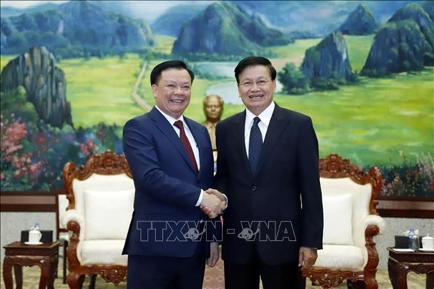 General Secretary of the Lao People’s Revolutionary Party and President of Laos Thongloun Sisoulith (R) welcomes Dinh Tien Dung, Politburo member of the Communist Party of Vietnam and Secretary of the municipal Party Committee, at the meeting in Vientiane on March 12. 