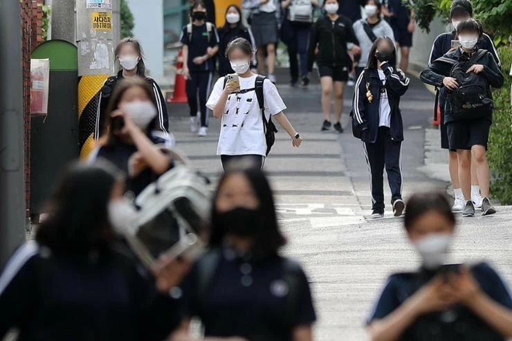 Students walk while looking at their mobile phones near a middle school in Seoul in this 2022 file photo. A bill has been proposed to restrict the use of mobile phones in schools. Newsis Students walk while looking at their mobile phones near a middle school in Seoul in this 2022 file photo. A bill has been proposed to restrict the use of mobile phones in schools. Newsis