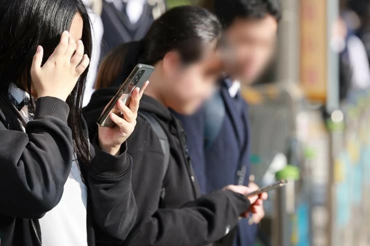 Students use smartphones while heading home outside a middle school in Seoul, Nov. 4. Yonhap Students use smartphones while heading home outside a middle school in Seoul, Nov. 4. Yonhap