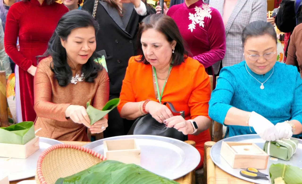 Phu nhân Ngô Phương Ly cùng các nữ Đại sứ tự tay gói bánh chưng. (Ảnh: Thành Long)