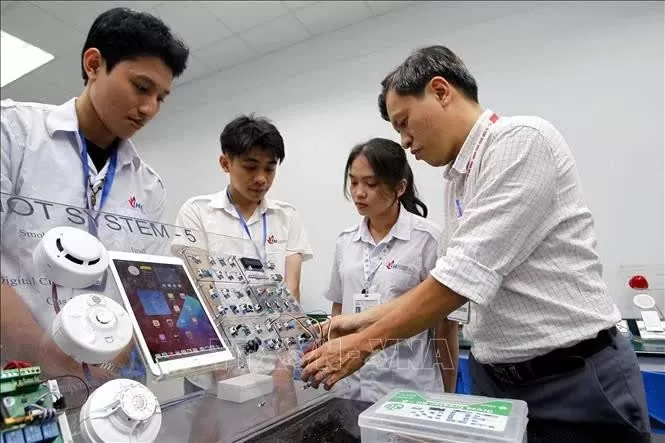 A lecturer from the faculty of electronic technology at the Ho Chi Minh City University of Industry provides guidance to students during a study and research session at the university's IoT and AI laboratory. (Photo: VNA)