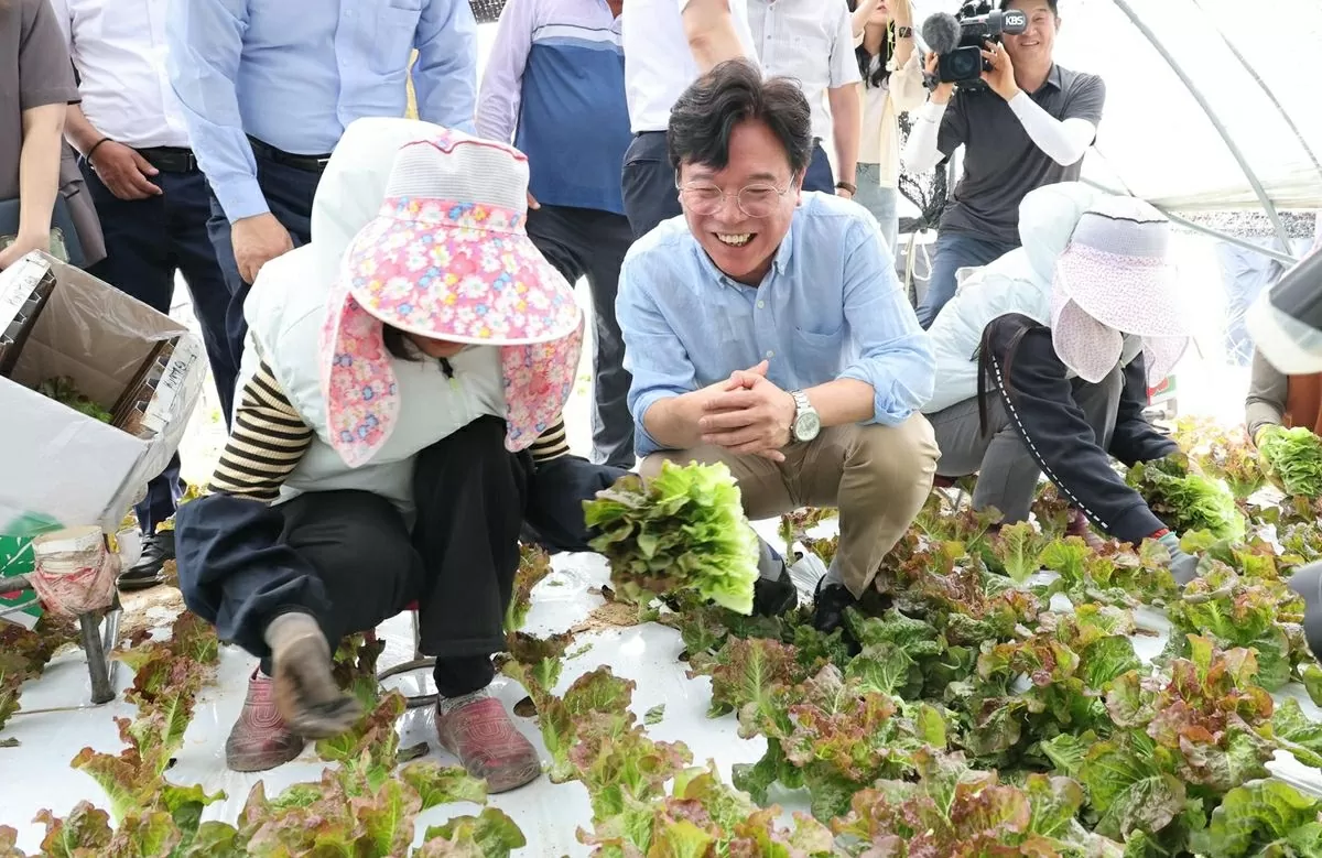Labor Minister Kim Young-hoon, center, talks with foreign workers harvesting lettuce during his visit to a greenhouse complex in Wanju, North Jeolla Province, Friday. Yonhap