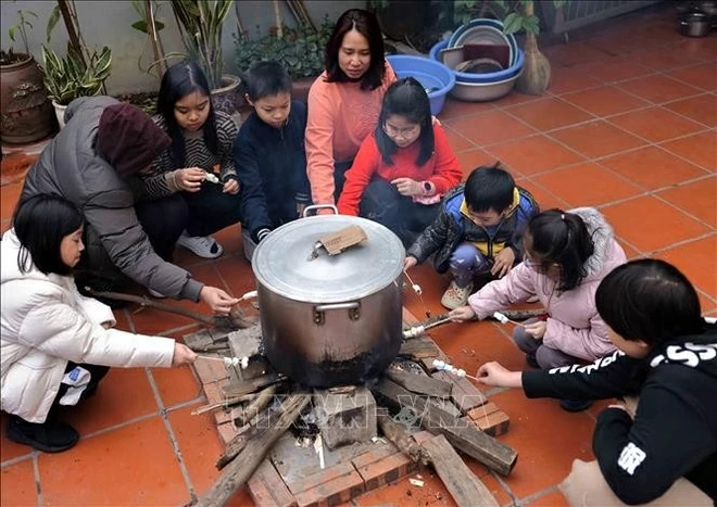 Watching the pot of banh chung is a cherished pastime for children whenever the Lunar New Year arrives. (Photo: VNA)