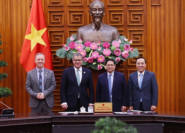Prime Minister Pham Minh Chinh (second, right), British Cabinet Minister and COP26 President Alok Kumar Sharma (second, left), and other officials pose for a photo at the meeting in Ha Noi on February 14. (Photo: VNA) 