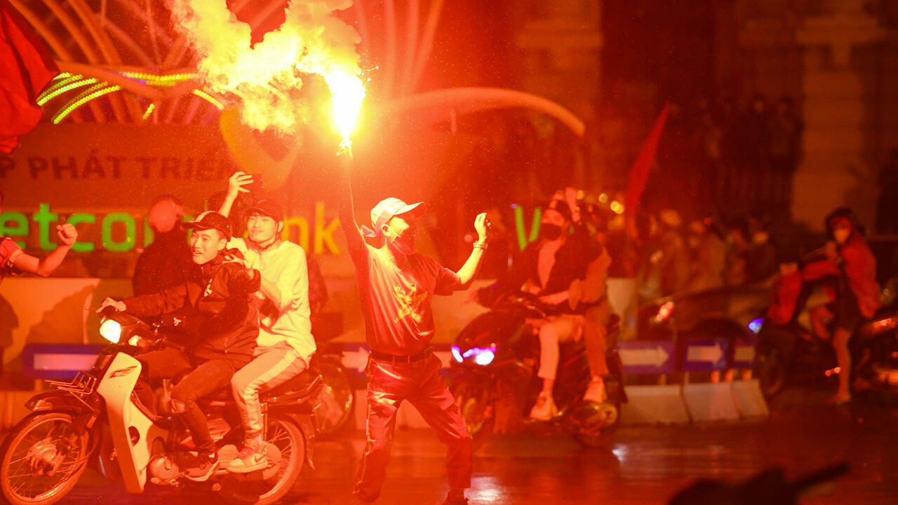 A supporter holds a flare as he celebrates Viet Nam's football win. (Photo: AFP)