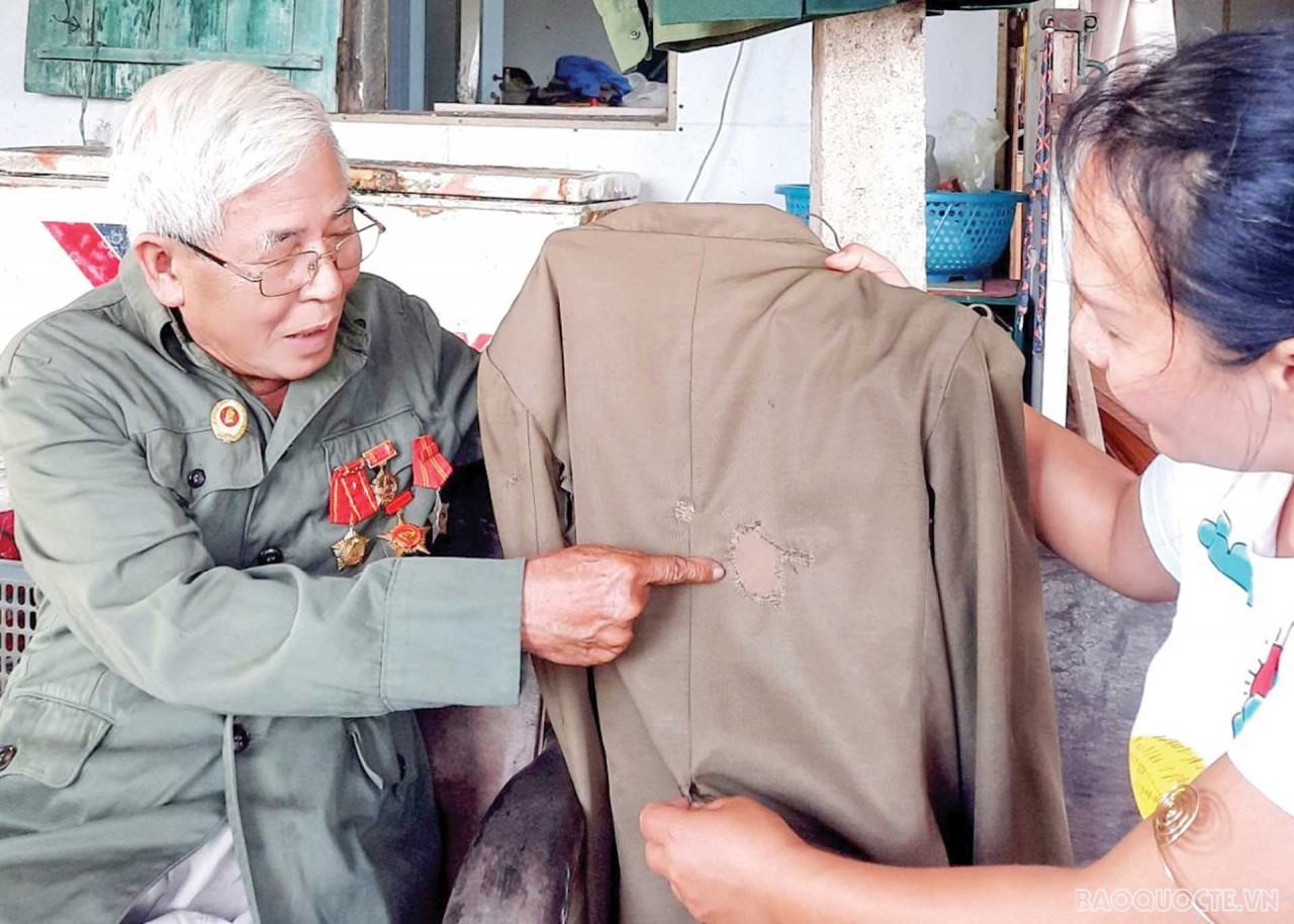 Le Mai showed us the suit burned by napalm bombs and patched by his wife. (Photo by Hanh Mi)