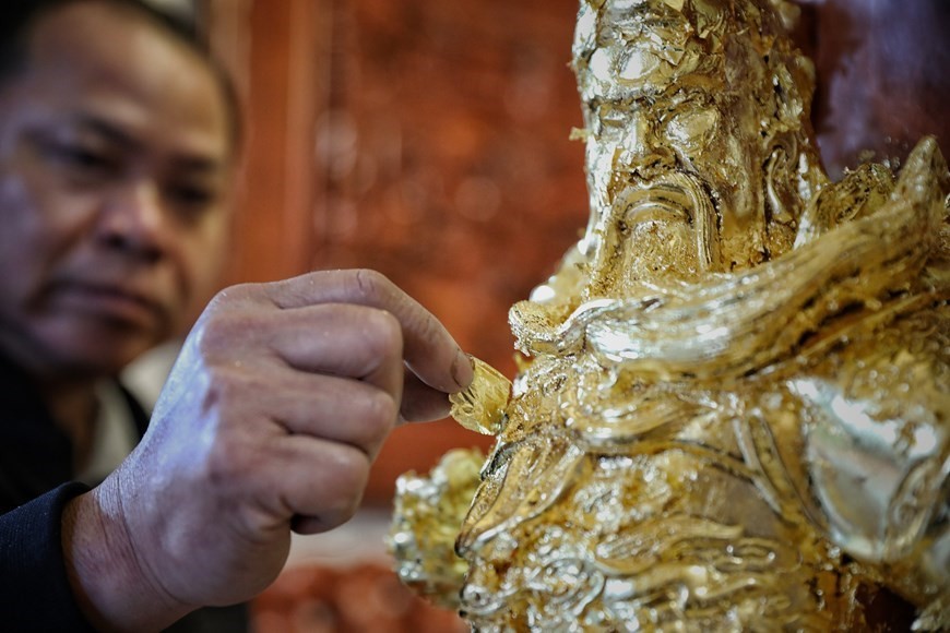 (03.13) An artisan in Kieu Ky village overlays a statue with super-thin gold leaves (Photo: VNA)