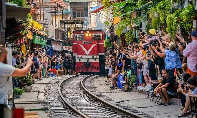 Foreign tourists use their smartphone to capture the moment when the train passes by a residential area in Hanoi. (Photo: Shutterstock).