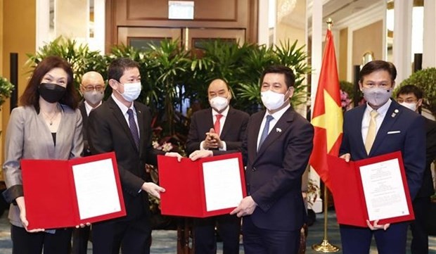 President Nguyen Xuan Phuc (third, right) witnesses the exchange of cooperation agreements between Vietnamese businesses and Sembcorp Group. (Photo: VNA)