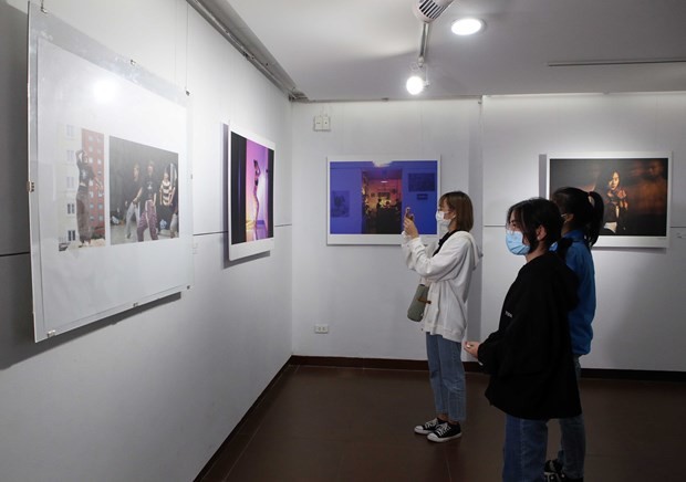 Visitors look at photos on display at the exhibiton. (Photo: VNA)