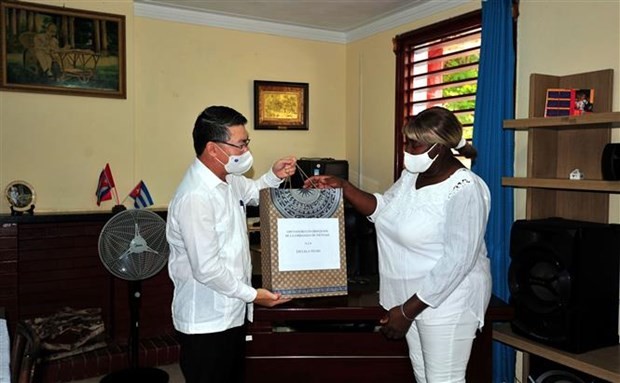 Vietnamese Ambassador Le Thanh Tung (L) presents gifts to head of 'Bac Ho' elementary school Milagros Negret Calderín(Photo: VNA)