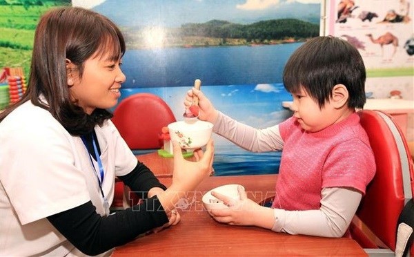 Giving life skill training to a child with disability (Photo: VNA)